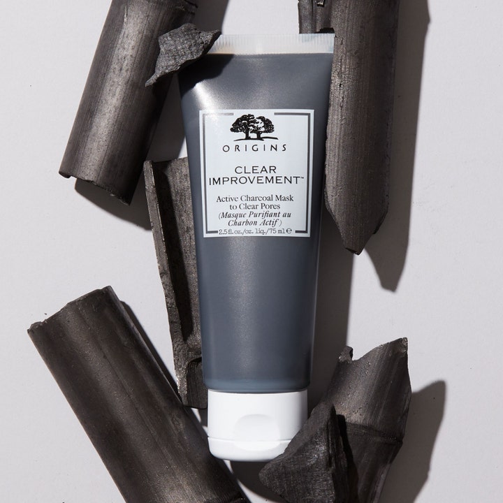 Origins Clear Improvement Active Charcoal Mask 75 ml ansiktsmask för tilltäppta porer omgiven av bitar av bambukol