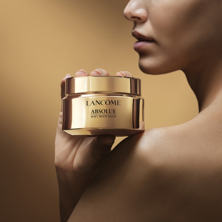 Lancôme Absolue Soft Body Balm 200 ml återfuktande kroppsbalsam i guldglänsande burk som hålls mot huden.