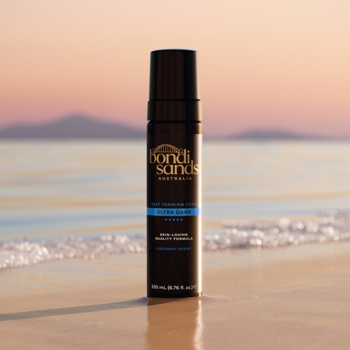Bondi Sands Self Tanning Foam Ultra Dark 200 ml tan mousse med kokosdoft i svart flaska på en strand vid havet.