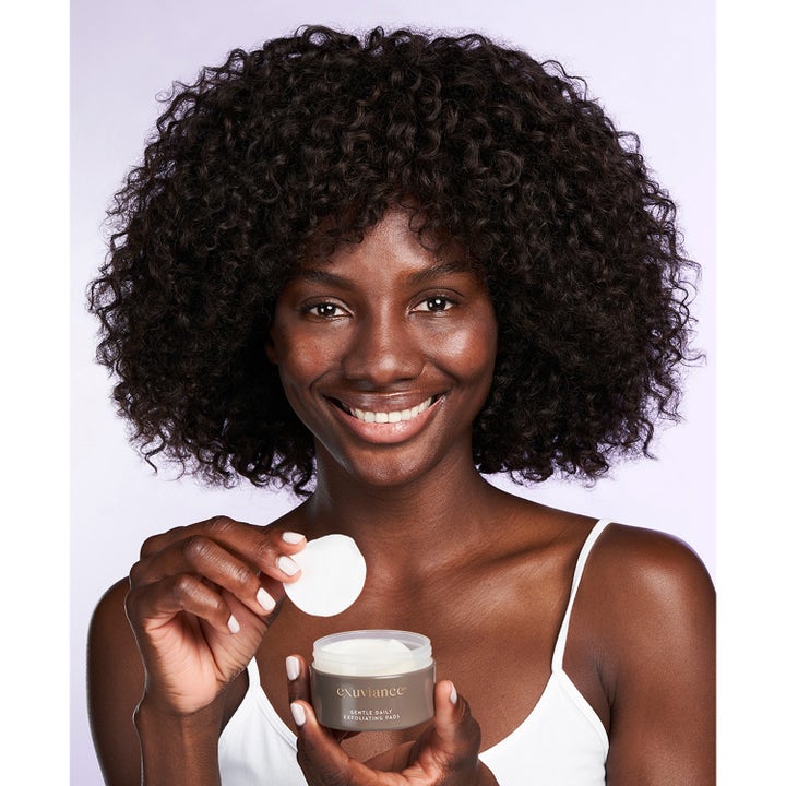 Exuviance Gentle Daily Exfoliating 60 Pads 55 ml ger lyster genom daglig exfoliering visad av kvinna med vit rondell.