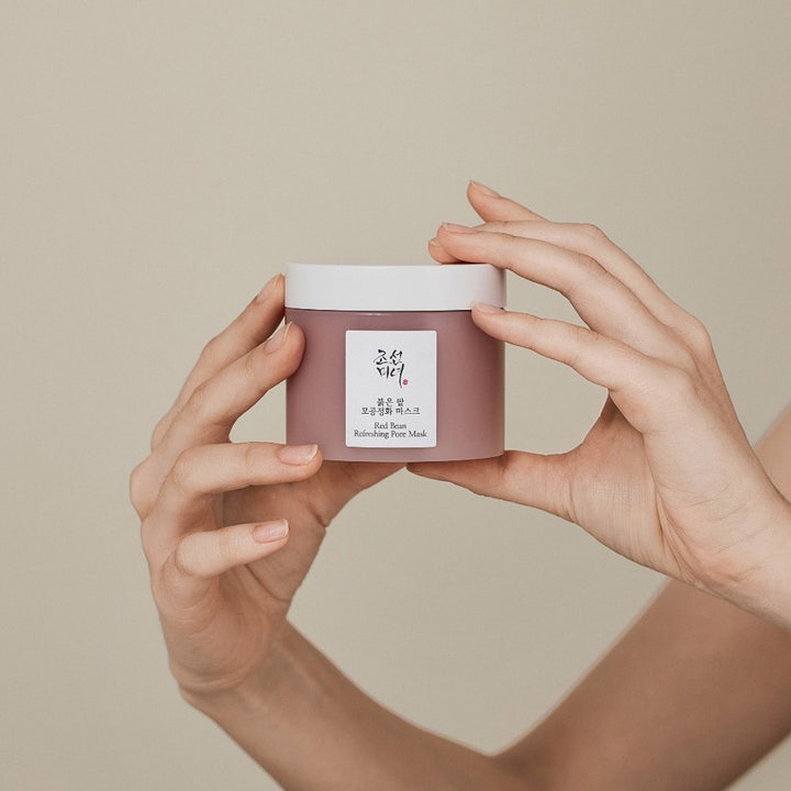 Beauty of Joseon Red Bean Refreshing Pore Mask 140 ml ansiktsmask för fet hy i lila burk som hålls av två händer.