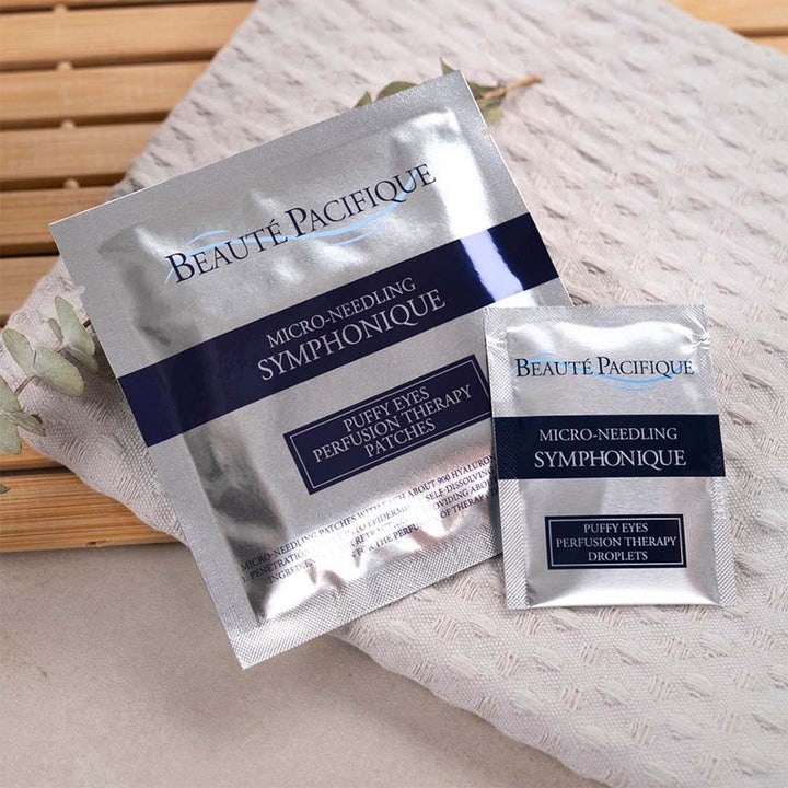 Beauté Pacifique Symphonique Puffy Eyes ögonbehandling i silverfärgade engångsförpackningar på en mjuk handduk.