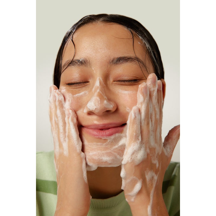 By Wishtrend Green Tea Enzyme Powder Wash 110 g ansiktsrengöring som skapar ett vitt skum i ansiktet på en person.