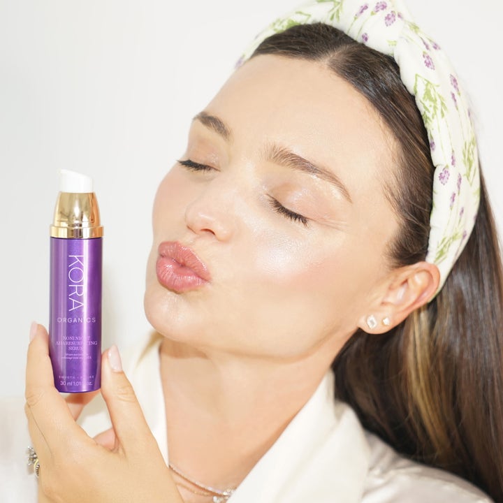 KORA Organics Noni Night AHA Resurfacing Serum 30 ml nattserum för aha exfoliering i lila flaska hållen av kvinna.