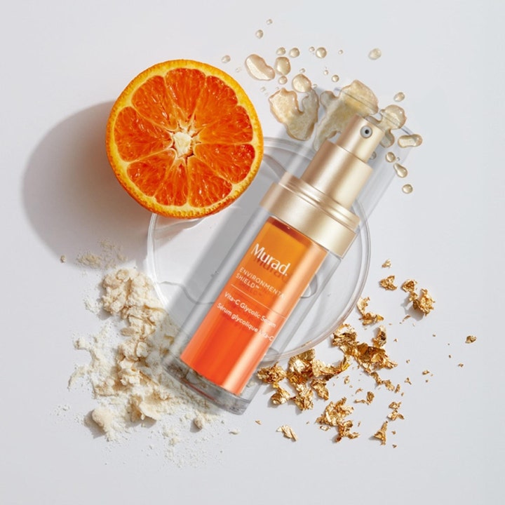 Murad Vita-C Glycolic Serum 30 ml uppljusande serum med glykolsyra bredvid en skivad apelsin och guld.