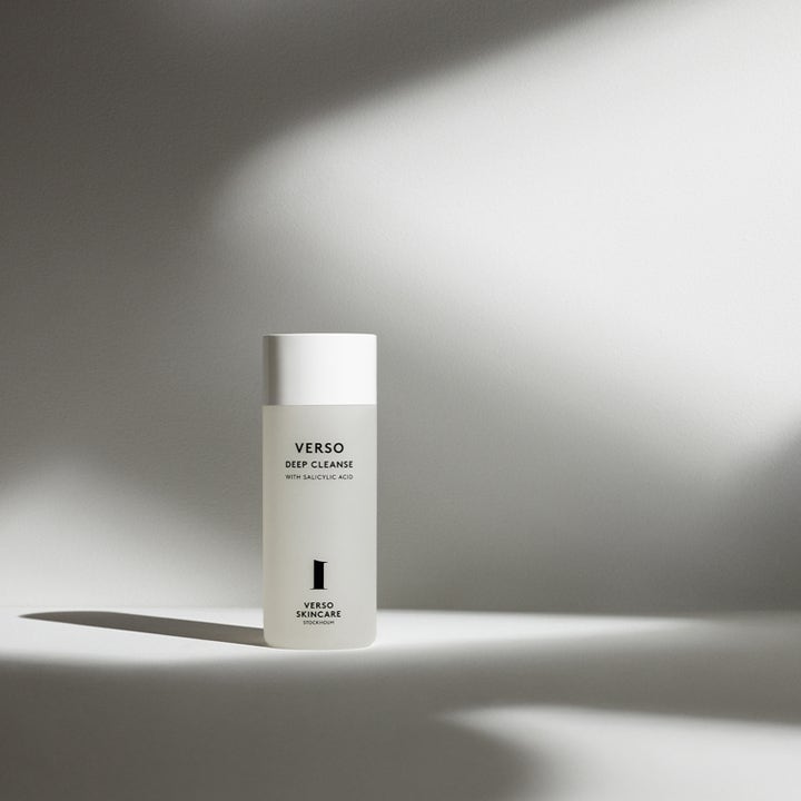 Verso N°1 Deep Cleanse 150 ml ansiktsrengöring med salicylsyra i frostad flaska mot en bakgrund med ljus och skuggor.