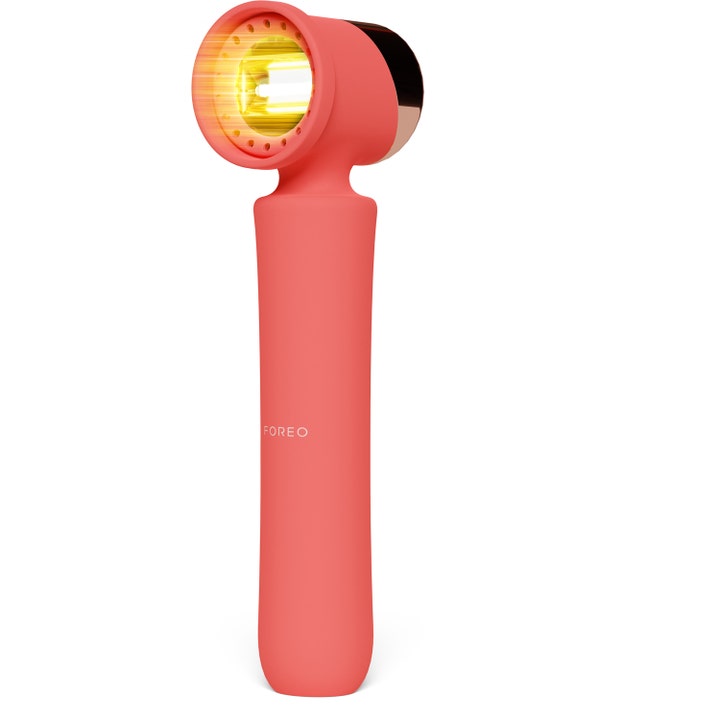 Foreo FAQ 201 ansiktsverktyg för rynkbehandling i korallrosa silikon med lysande gult LED-ljus.