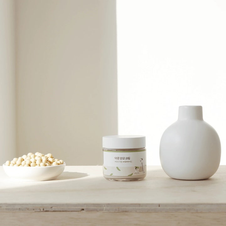 Round Lab Soybean Nourishing Cream 80 ml ansiktskräm för torr hud med sojaböna i burk bredvid en vit vas.