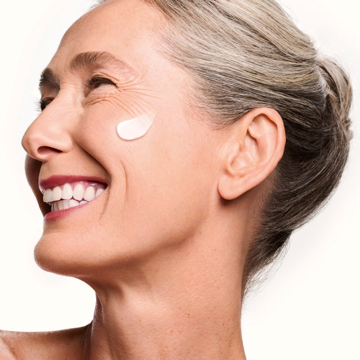 Shiseido Vital Perfection Concentrated Supreme Cream Refill 50 ml lyftande dagkräm på en leende kvinnas kind.