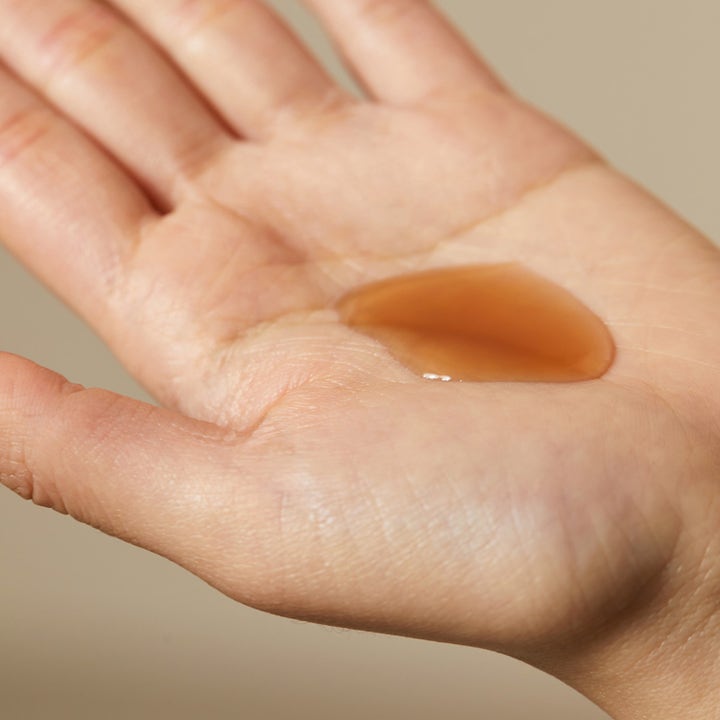 Hyggee Natural Repair Serum 30 ml anti-rynk naturligt serum med bärnstensfärgad flytande textur i en handflata.