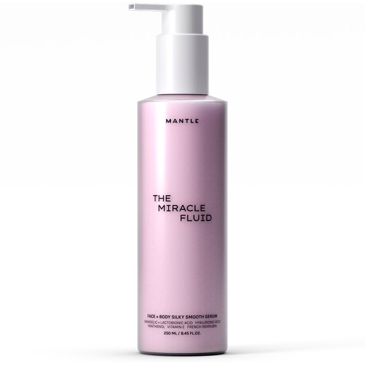Mantle The Miracle Fluid 250 ml lystergivande serum för ansikte och kropp i en ljusrosa flaska med vit pump