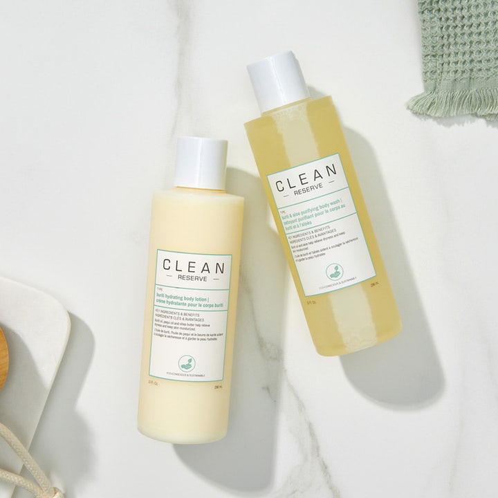 Clean Reserve Buriti & Aloe Shower Gel 296 ml och body lotion i vita plastflaskor på en ljus marmoryta.
