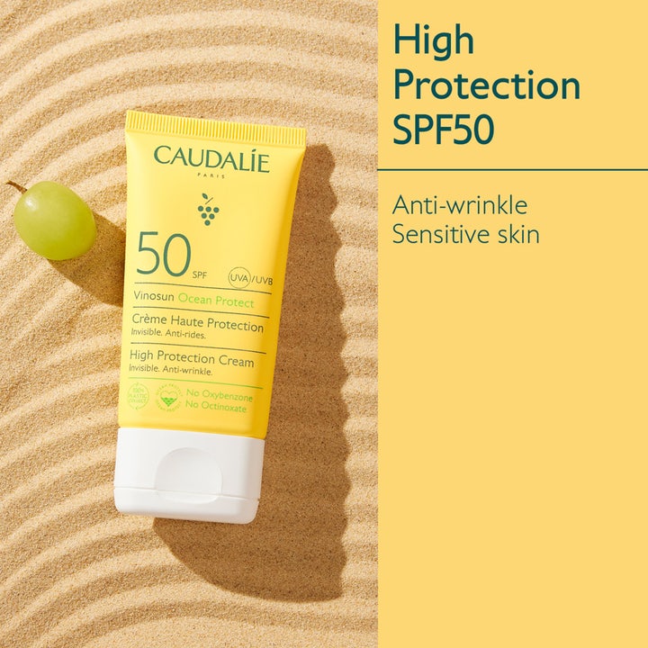 Caudalie Vinosun Protect Cream 50 ml ansiktssolkräm hög skydd mot rynkor i gul tub på sand med en grön druva.