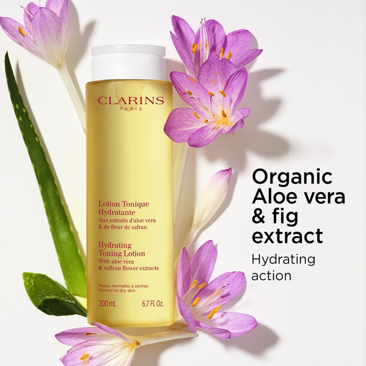 Clarins Hydrating Toning Lotion 400 ml återfuktande toner i flaska omgiven av lila blommor och aloe vera.
