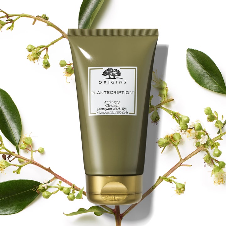 Origins Plantscription Anti-aging Cleanser 150 ml ansiktsrengöring med växtextrakt i grön tub bland vackra blad.
