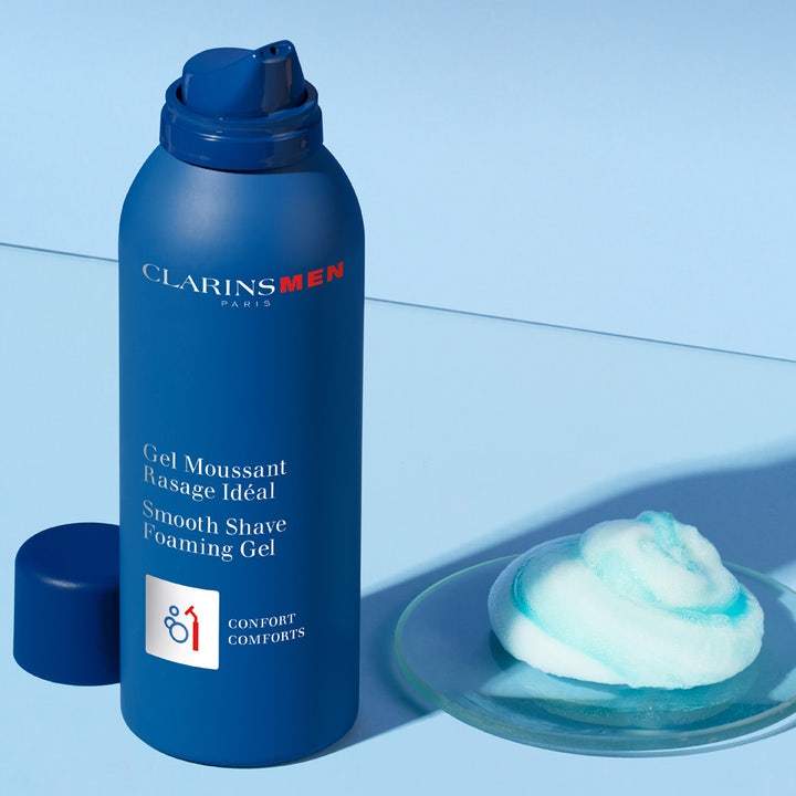 Clarins Men Shave Gel 150 ml gel för rakning i blå sprayflaska med vitt och blått rakskum på ett glasfat.