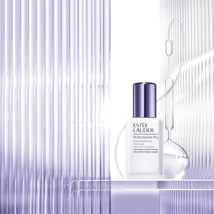 Estée Lauder Perfectionist Pro 30 ml c vitamin serum för jämn hudton i vit flaska framför räfflat lila glas