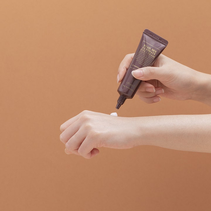 Benton Snail Bee Ultimate Eye Cream 30 g anti-aging ögonkräm med bivenom som appliceras från en brun tub på handen.