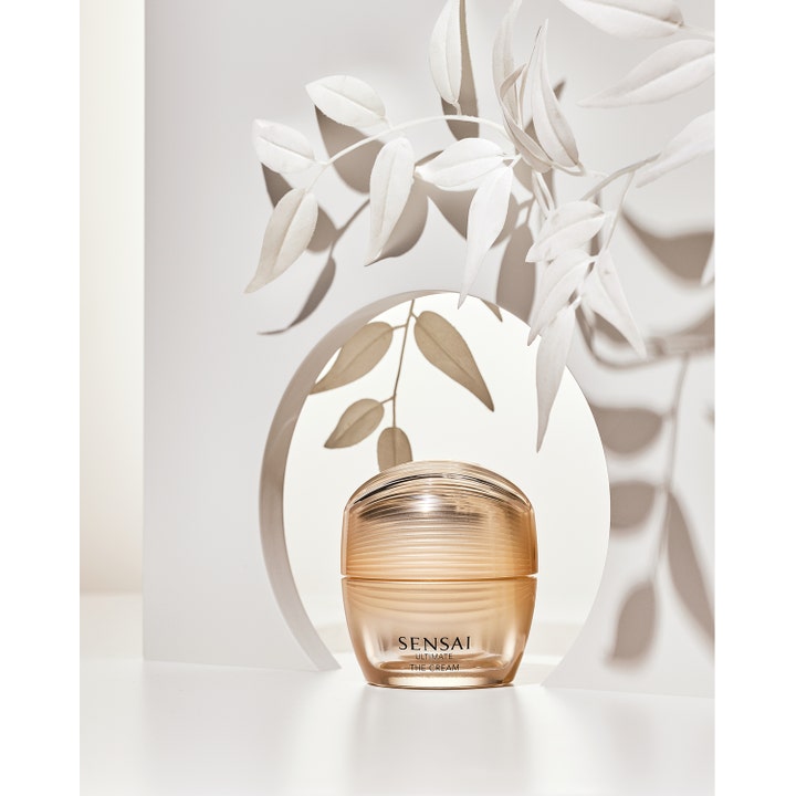 Sensai Ultimate The Cream 40 ml anti-age kräm för fastare hud i guldglänsande burk omgiven av vita blad.