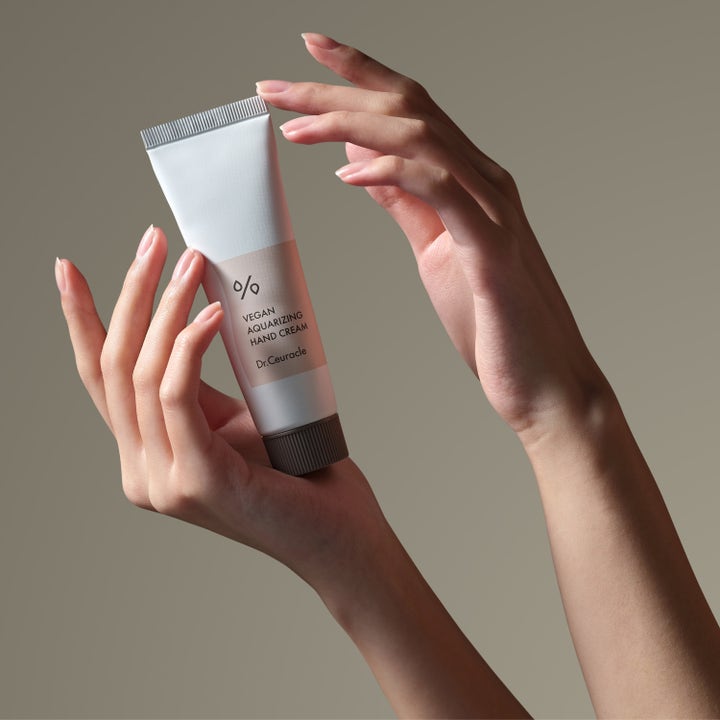 Dr. Ceuracle Vegan Aquarizing Hand Cream 50 ml närande handkräm i vit tub som hålls mellan två händer