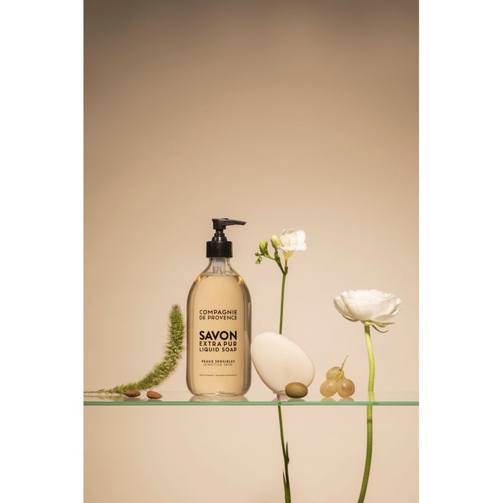 Compagnie de Provence Liquid Marseille Soap 495 ml känslig tvål i glasflaska omgiven av blommor och mandlar