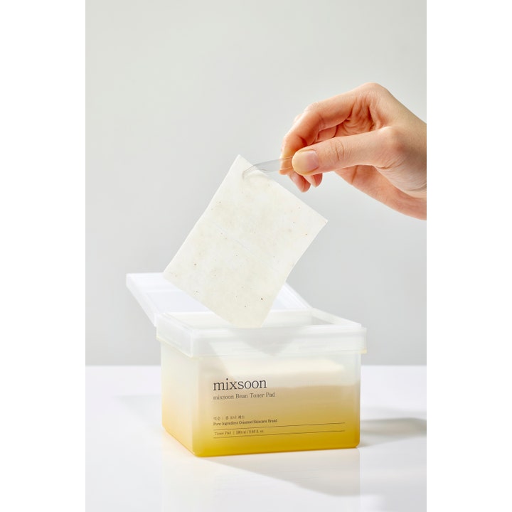Mixsoon Bean Toner Pad 70 st återfuktande ansiktspad med bönextrakt lyfts med pincett ur en frostad burk.