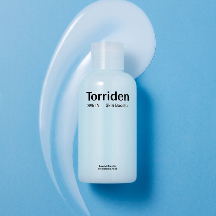 Torriden DIVE-IN Skin Booster 200 ml återfuktande ansiktsvatten i ljusblå flaska framför en krämig textur.