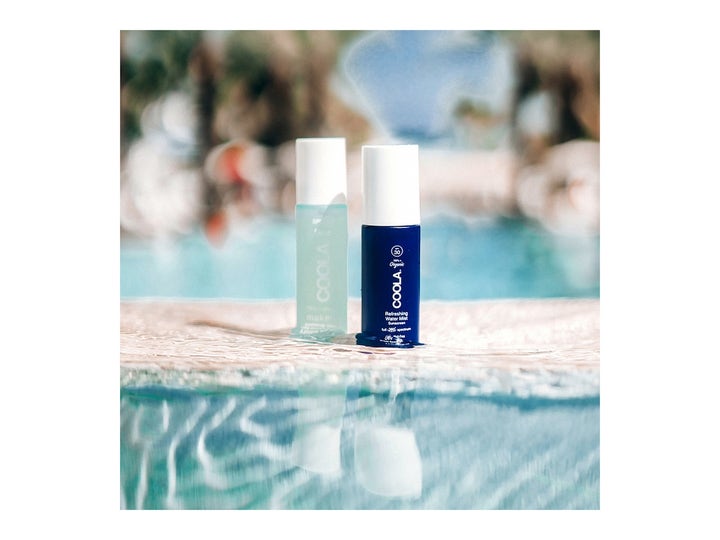 COOLA Refreshing Water Mist 50 ml återfuktande ansiktsspray anti-pollution i blå flaskor placerade vid vatten.