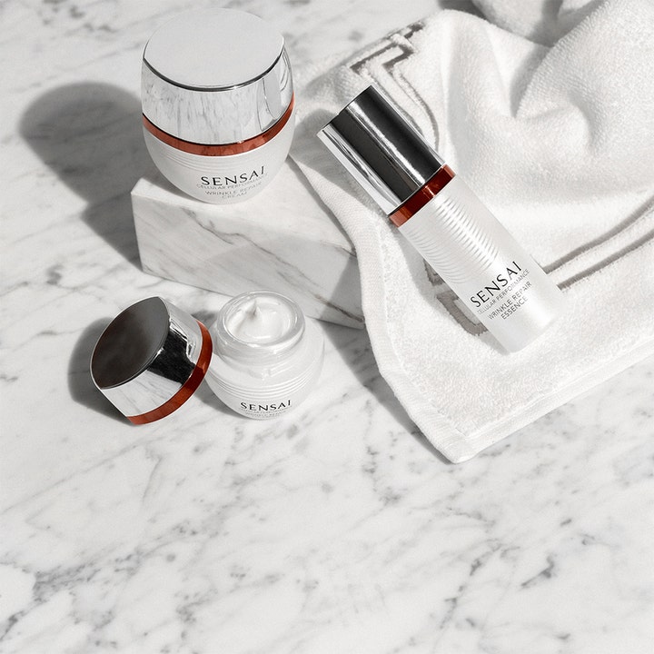 Sensai Cellular Performance Wrinkle Repair Eye Cream 15 ml reducerar rynkor i öppen vit burk med krämig textur på marmor.