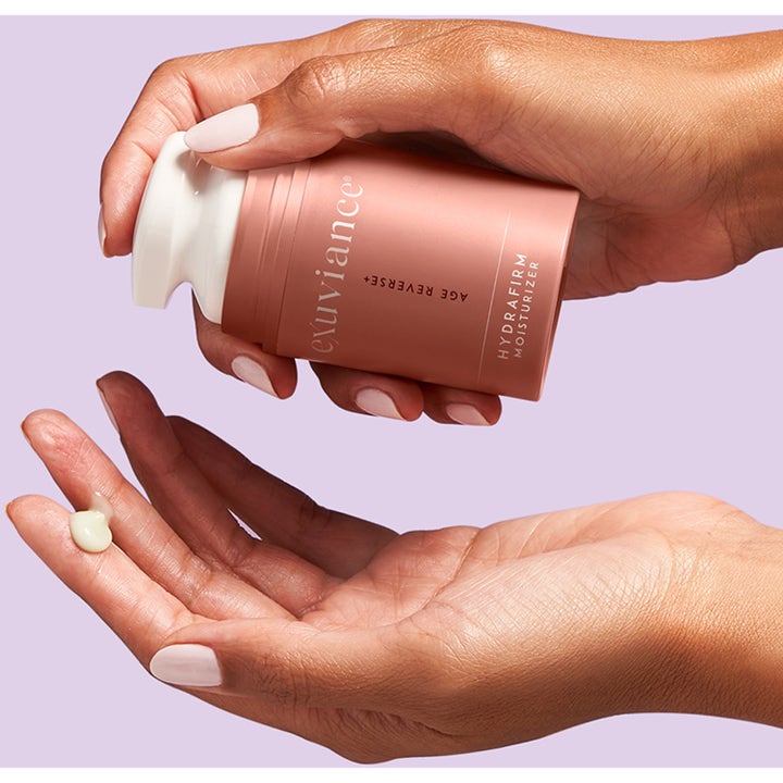 Exuviance Age Reverse Hydrafirm 50 g fast ansiktskräm återfuktande i rosa pumpflaska med krämig klick på en hand