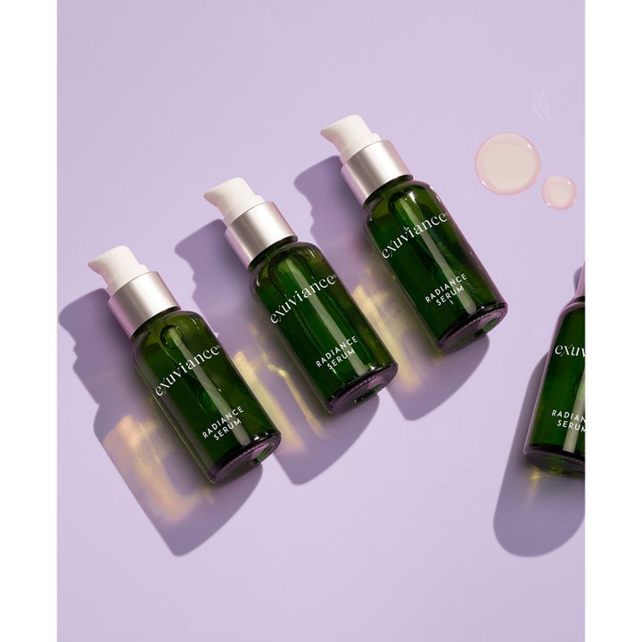 Exuviance Radiance Serum 30 ml antiage serum i gröna glasflaskor med pump på lila bakgrund