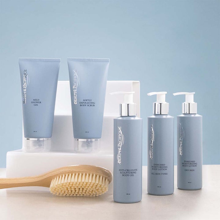Beauté Pacifique berikad kroppslotion och bodylotion för normal hud i ljusblå förpackningar bredvid en kroppsborste.