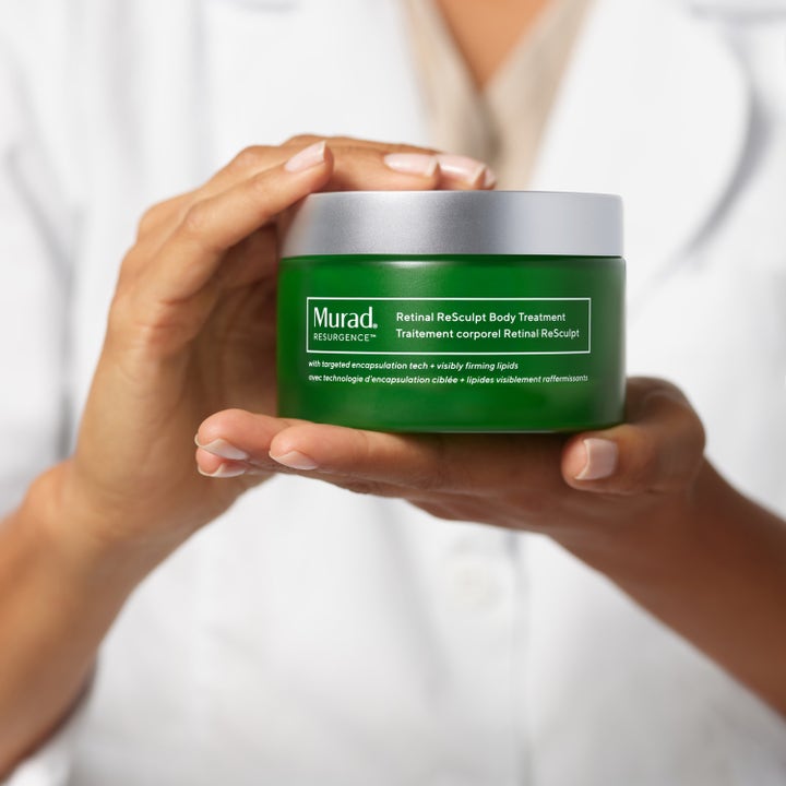 Murad Retinal ReSculpt Body Treatment 148 ml uppstramande kroppsvård i grön burk som hålls i händerna.