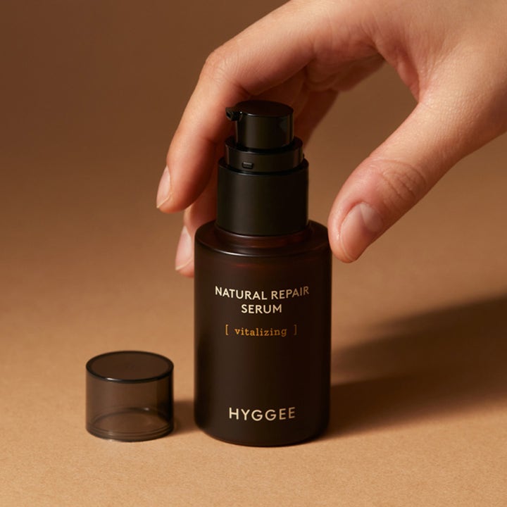 Hyggee Natural Repair Serum 30 ml vitaliserande anti-rynk naturligt serum i mörk glasflaska som hålls av en hand.