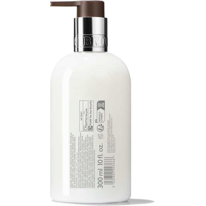Väldoftande Molton Brown Delicious Rhubarb &amp; Rose 300 ml handlotion i vit flaska med brun pump visar baksidans etikett.