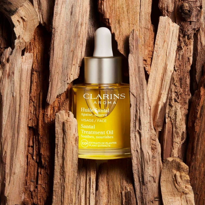Clarins Santal Face Treatment Oil 30 ml lugnande ansiktsolja i glasflaska omgiven av grov träbark.