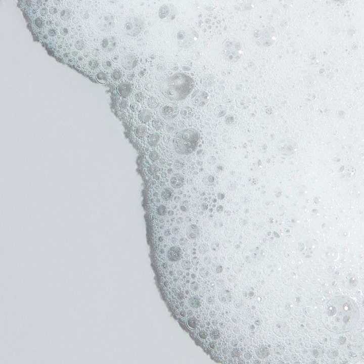 Dermalogica Clearing Skin Wash 500 ml ansiktsrengöring mot finnar visas som ett vitt, luftigt skum med bubblor.