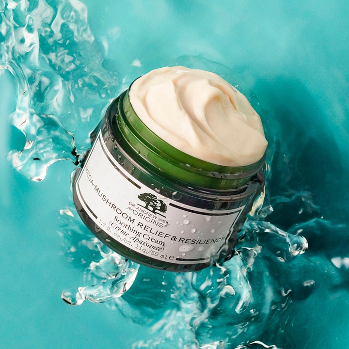 Origins Dr. Weil Mega-Mushroom 50 ml lugnande ansiktskräm mot rodnad i öppen grön burk bland vattenstänk