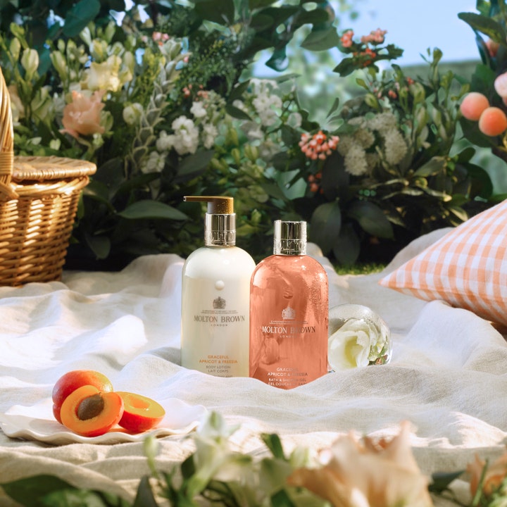 Molton Brown Graceful Apricot & Freesia 300 ml fuktgivande bodylotion för torr hud i vit pumpflaska i en lyxig picknickmiljö