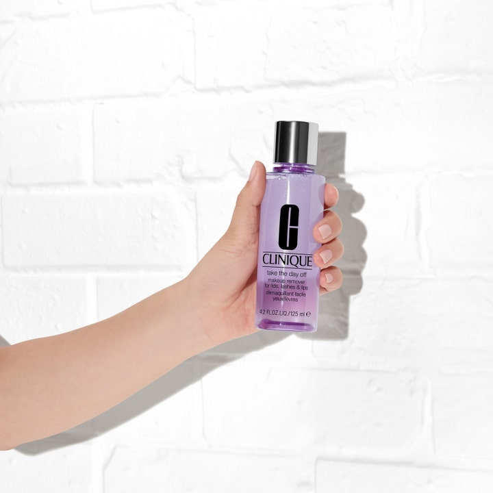 Clinique Take the Day Off 125 ml effektiv sminkborttagare i lila flaska med silverlock som hålls i en hand