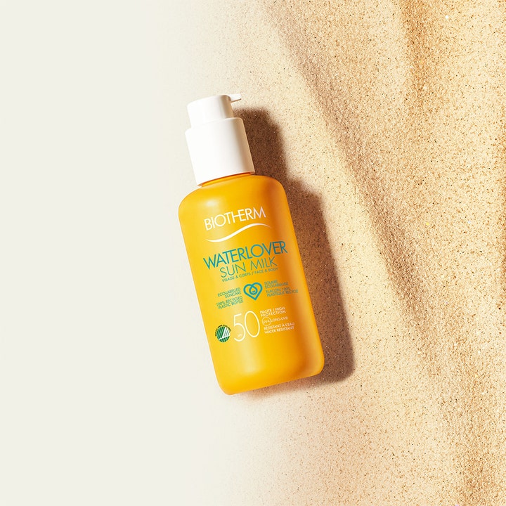 Biotherm Waterlover Sun Milk 200 ml miljövänlig solskydd SPF 50 i gul pumpflaska liggandes på sand