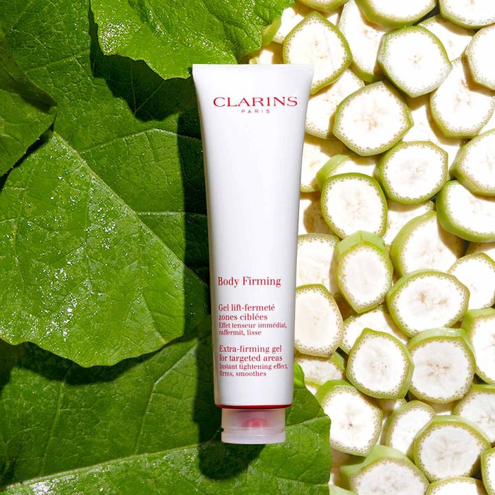 Clarins Body Firming Gel 150 ml uppstramande kroppsgel i vit tub på en bädd av gröna blad och fruktskivor.