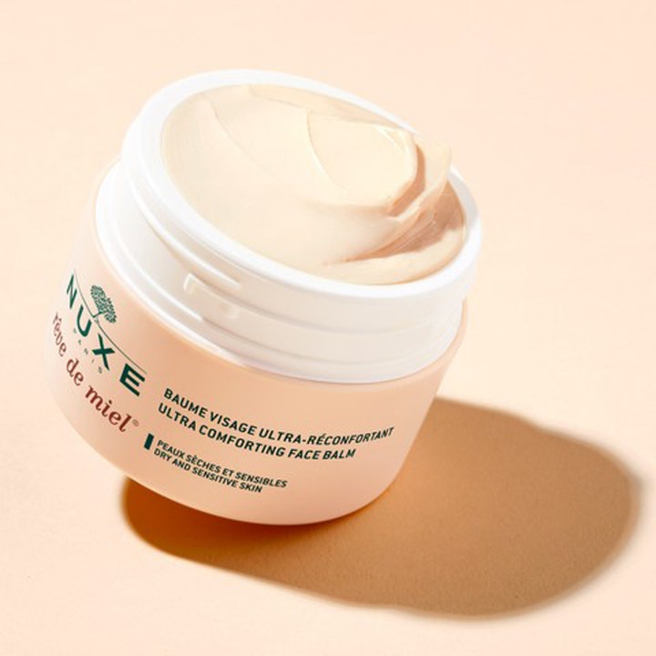 Nuxe Rêve de Miel 50 ml lugnande balm torr hud visar en fyllig beige kräm i en öppen persikofärgad burk.