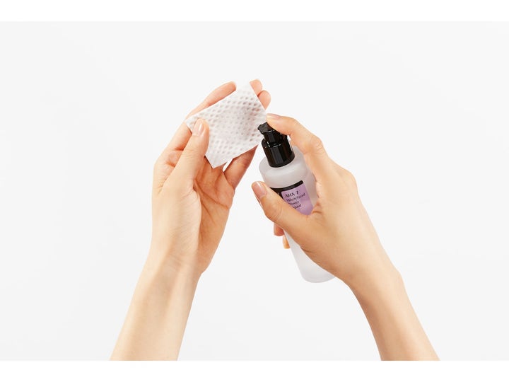 COSRX AHA 7 Whitehead Power Liquid 100 ml aha exfoliering ansiktsvatten appliceras på bomullspad från en frostad flaska.