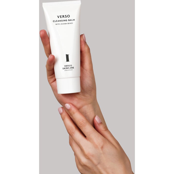Verso Cleansing Balm With Jojoba Beads 100 ml ansiktsrengöring i vit tub som hålls i en hand för en renande effekt.