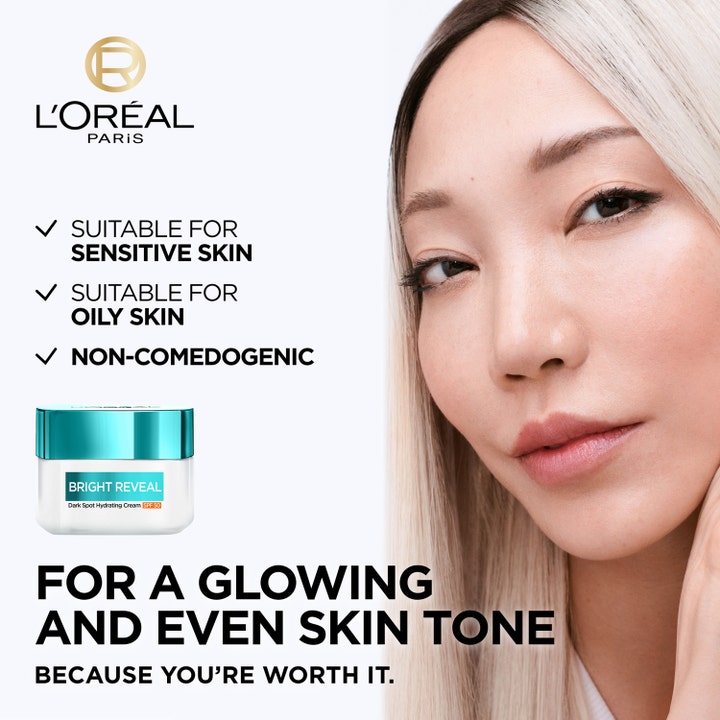 L'Oréal Paris Bright Reveal 50 ml återfuktande dagkräm SPF 50 mot mörka fläckar visas bredvid kvinna med jämn hudton.