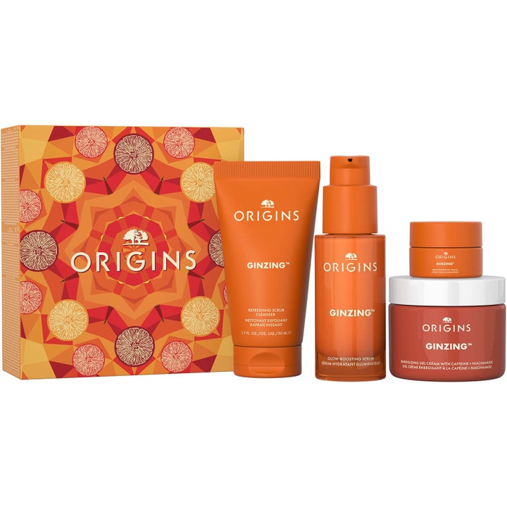 Origins GinZing energiboostande hudvårdsset för ljus hud ger lyster med orangea tuber och burkar i en mönstrad ask.