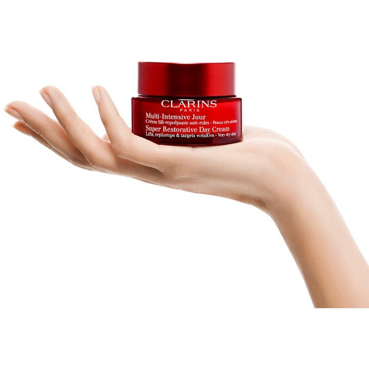 Clarins Super Restorative Day Cream 50 ml intensivt återfuktande dagkräm i röd glasburk vilande i en hand.