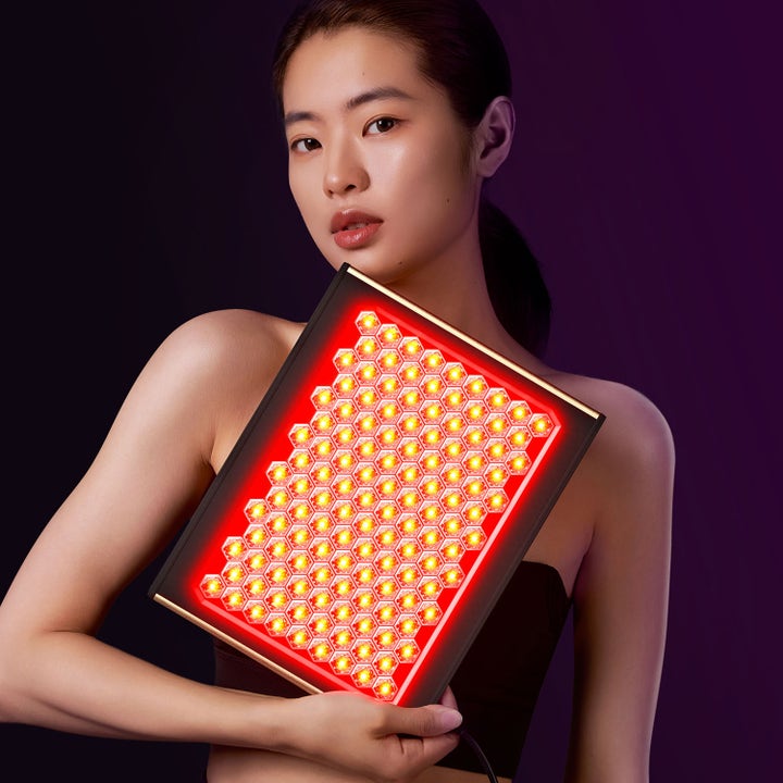 FAQ Swiss FAQ™ Led Panel 1 st hudvårdsverktyg för led-terapi som en kvinna håller i med rött lysande bikupemönster