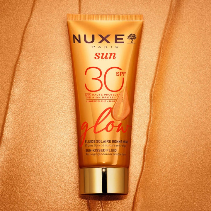 Nuxe Sun-Kissed Fluid 40 ml solkräm för ansiktet med SPF 30 i orange tub på en skimrande gyllene bakgrund.